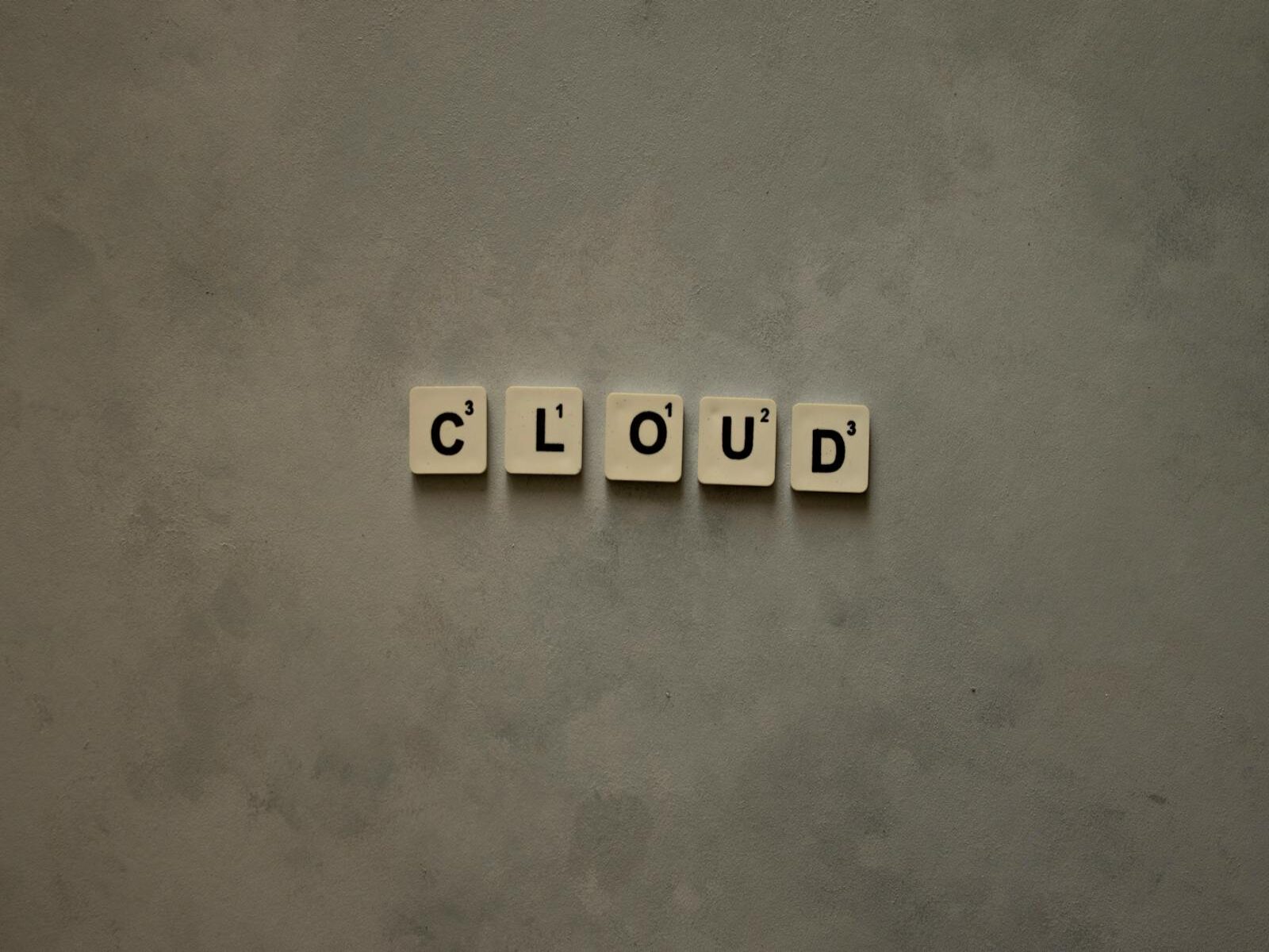 40% en costos operativos de TI, Scrabble tiles arranged to spell 'cloud' on a neutral textured backdrop, creative concept image.